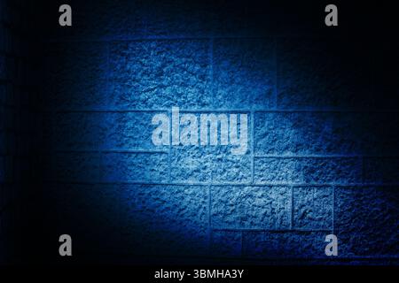 La parete in calcestruzzo è mostrata con un design piatto, con un fascio di luce blu che espone una superficie ruvida Foto Stock