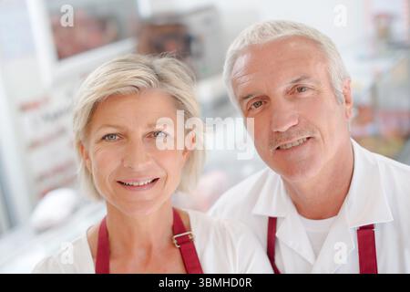 una coppia sorridente che indossa grembiuli Foto Stock