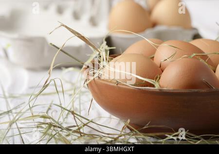 Materie organica marrone le uova di gallina in vaso di creta sulla cucina bianca tavolo in legno Foto Stock