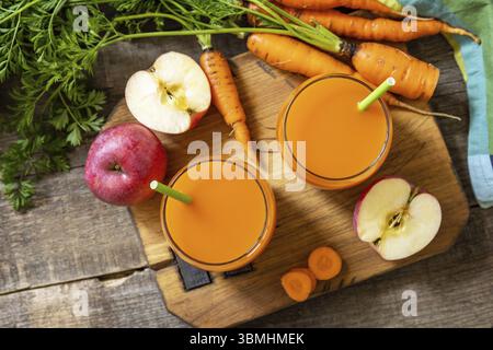 Succo naturale fresco, concetto di cibo sano. Bicchiere di succo di mela e carota fresco su un tavolo rustico in legno. Vista dall'alto sfondo piatto. Copia spac Foto Stock