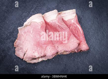 Porzione di Roastbeef affettato su una lastra di ardesia (messa a fuoco selettiva) Foto Stock