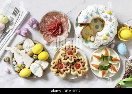 Cena festiva, brunch di Pasqua. Scena di Pasqua con un assortimento di cottura, dessert, uova farcite e uova tinte su uno sfondo di marmo. Visualizza da Foto Stock