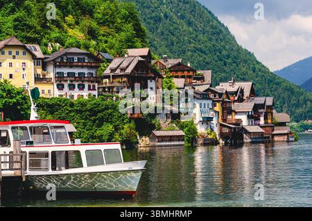 Hallstadt in Austria. Una barca è ormeggiata davanti a una casa. La casa è circondata da alberi e ha un tetto verde Foto Stock