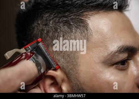 Taglio di capelli ravvicinati di un ragazzo dai capelli scuri. fotografia cinematografica Foto Stock