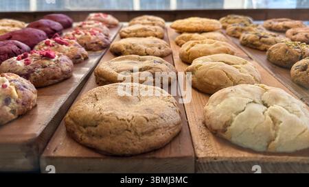 Biscotti rotondi appena sfornati con vari ingredienti, esposti su una superficie rustica in legno. Foto Stock