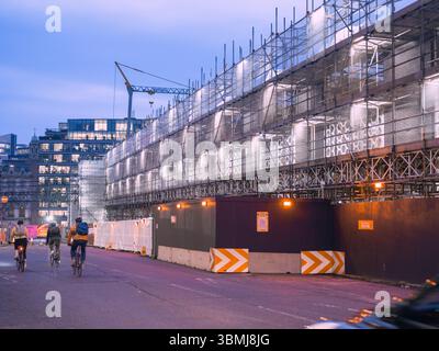 Regno Unito, Londra, 30 giugno 2025. Vista serale dell'impalcatura del cantiere illuminata da ciclisti che passano in una ricostruzione del centro di Londra Foto Stock