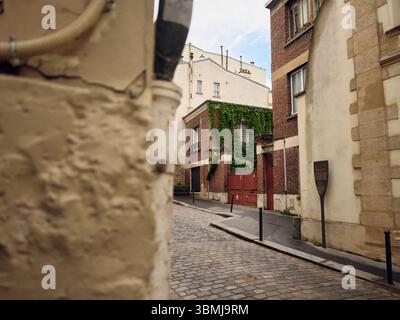 Edificio coperto di edera in stretta strada acciottolata di parigi Foto Stock