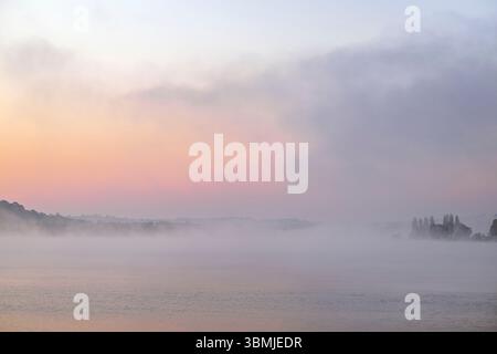 Lago Blagdon, Somserset all'alba in una mattinata nebbiosa in primavera con una splendida alba pallida che si mostra attraverso la nebbia Foto Stock