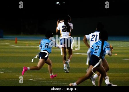 Le ragazze sbandierano l'azione calcistica durante la partita notturna, le giocatrici saltano per catturare la palla a mezz'aria mentre i difensori inseguono, energico momento sportivo scolastico, atletica giovanile Foto Stock