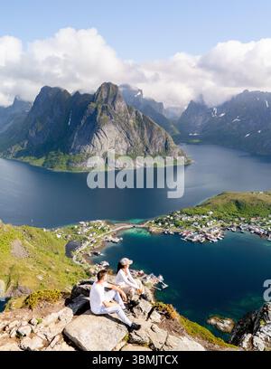 Due escursionisti godono di un panorama mozzafiato da una cima di montagna in Norvegia. Coppia in escursione sul monte Reinebringen Lofoten Norvegia Foto Stock