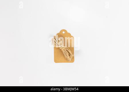 Etichetta in carta kraft marrone vuota con stringa di iuta per appendere su sfondo bianco Foto Stock