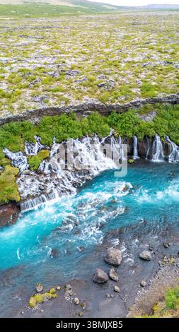Esplora le splendide cascate di Barnafoss e Hraunfossar che si infrangono su terreni rocciosi, circondati da una vegetazione lussureggiante e dalle vibranti acque blu delle ghiacciaie e paesaggi affascinanti. Foto Stock