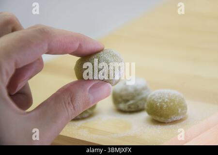 Dolce mochi verde in mano Foto Stock