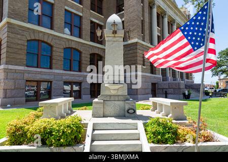 La bandiera degli Stati Uniti d'America vola accanto al Confederate Soldiers' Memorial fuori dal tribunale della contea di Johnson a Cleburne, Texas, USA. Foto Stock