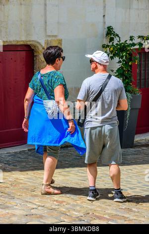 Coppia di turisti in abito estivo che cammina su strade acciottolate nel centro storico - Loches, Indre-et-Loire (37), Francia. Foto Stock