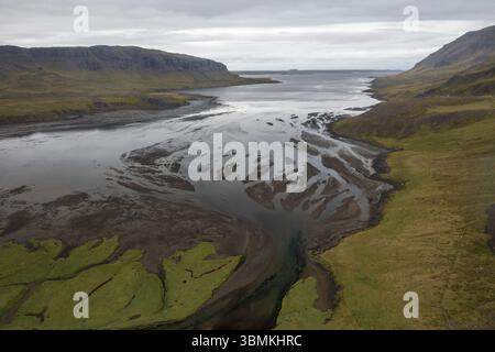 Vista aerea del fiume che incontra l'oceano, con un netto contrasto tra aspre montagne e acque tranquille, Aðalgata, Sveitarfélagið Stykkishólmur, Islanda Foto Stock