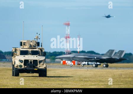 Lakenheath, Regno Unito. 27 giugno 2025. Un Solitary Joint Light Tactical Vehicle (JLTV) si trova sul campo di aviazione della RAF Lakenheath con due F-35A dell'USAF sullo sfondo. La base è la sede del 48th Fighter Wing a Suffolk, in Inghilterra. L'L-ATV è stato sviluppato da Oshkosh come sostituto dell'Humvee per soddisfare le esigenze di un Light Combat Tactical All-Terrain Vehicle per l'esercito degli Stati Uniti. Si tratta di un veicolo leggero multiuso/combattimento multiruolo. Crediti: Mark Bullimore/Alamy Live News Foto Stock
