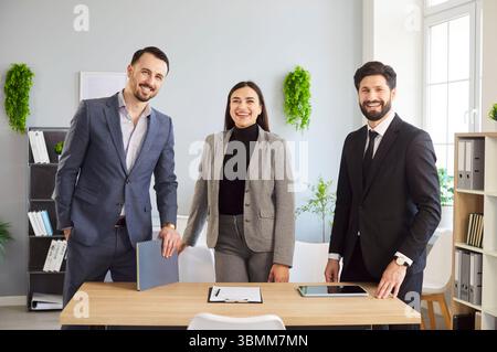 Ambiente d'ufficio accogliente, due uomini, una donna sorridente, ritratto di gruppo di colleghi professionisti Foto Stock