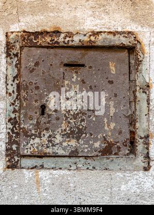 Vecchia scatola di elemosina arrugginita sulla parete con intonaco spellato e spazio per copiare Foto Stock