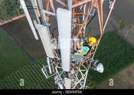 Tecnici che si arrampicano su una torre di rete con dispositivi di sicurezza, risoluzione dei problemi relativi alla torre di rete mobile, torre di telefonia mobile, antenna radio, rete wireless Foto Stock