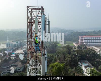Tecnici che si arrampicano su una torre di rete con dispositivi di sicurezza, risoluzione dei problemi relativi alla torre di rete mobile, torre di telefonia mobile, antenna radio, rete wireless Foto Stock