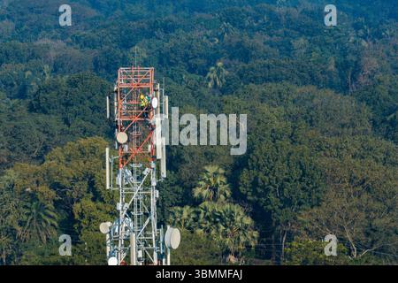 Tecnici che si arrampicano su una torre di rete con dispositivi di sicurezza, risoluzione dei problemi relativi alla torre di rete mobile, torre di telefonia mobile, antenna radio, rete wireless Foto Stock
