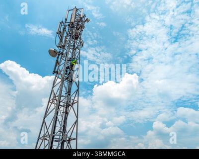 Tecnici che si arrampicano su una torre di rete con dispositivi di sicurezza, risoluzione dei problemi relativi alla torre di rete mobile, torre di telefonia mobile, antenna radio, rete wireless Foto Stock