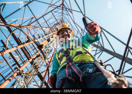 Tecnici che si arrampicano su una torre di rete con dispositivi di sicurezza, risoluzione dei problemi relativi alla torre di rete mobile, torre di telefonia mobile, antenna radio, rete wireless Foto Stock