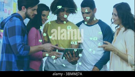 I membri del team collaborano intorno ai tablet in studio, visualizzando le icone di rete con note sulla lavagna bianca Foto Stock