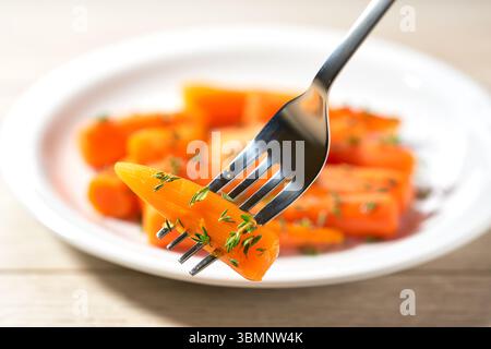 Carote glassate al miele arrosto fatte in casa con timo pronte da mangiare, concentrazione selettiva. Foto Stock