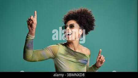 Punta, danza e donna africana in studio con moda, energia e mosse per festeggiare. Persona felice, eccitata e gesto per il groove, occhiali da sole Foto Stock