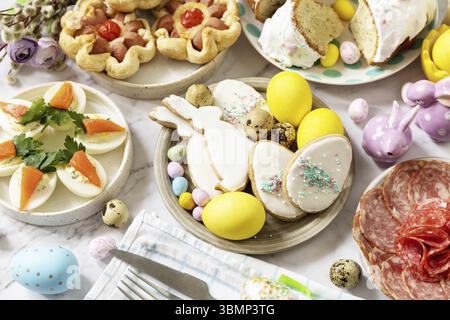 Cena di Natale, brunch di Pasqua. Tavola di Pasqua con un assortimento di piatti da forno, dessert, uova ripiene e uova tinte su sfondo di marmo Foto Stock
