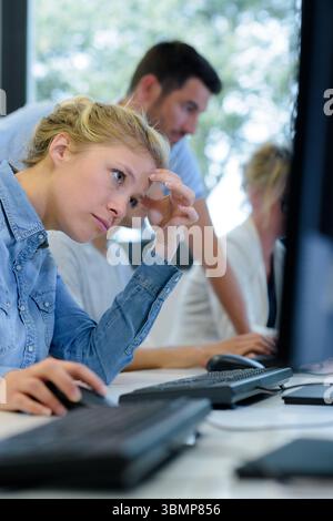 vista laterale degli studenti stanchi che ascoltano una lezione noiosa Foto Stock