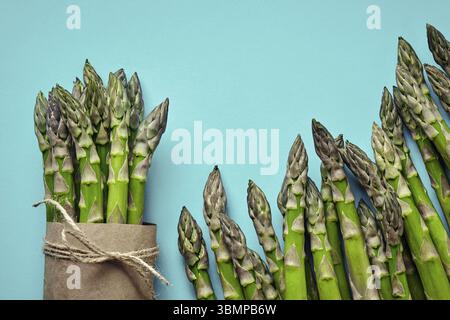 Bunch of an edible, fresh stalks of asparagus isolated on blue background. Green vegetables, top view. Healthy meal. Spring harvest, agricultural farm Foto Stock