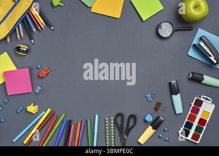 Foto piatta di una scrivania da lavoro con materiale scolastico, come penne in feltro, tre pennarelli, astuccio giallo, gomme, bottoni, graffette, sci Foto Stock