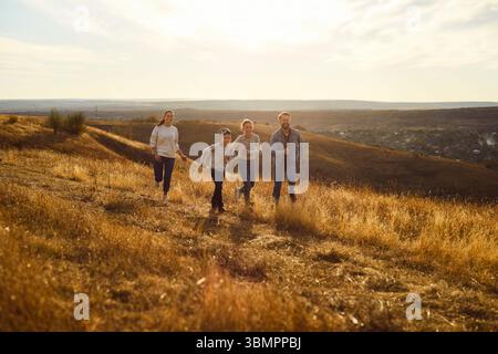 Una famiglia felice che corre all'aperto, si sente libera e rilassata nella natura, posare sul prato Foto Stock