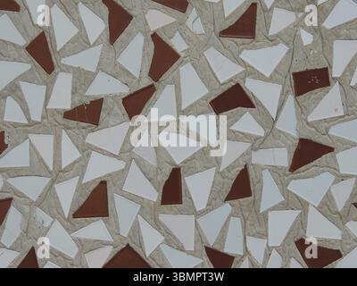 astrazione a mosaico di piastrelle triangolari rotte di colore bianco e bordeaux nella consistenza di un muro di cemento, decorazione semplice Foto Stock