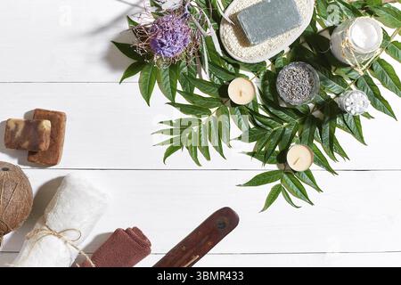 Set benessere con asciugamano e sapone su sfondo bianco di legno con foglie verdi. Vista dall'alto. Spazio di copia. Vita morta. Simulazione. Disposizione piatta Foto Stock