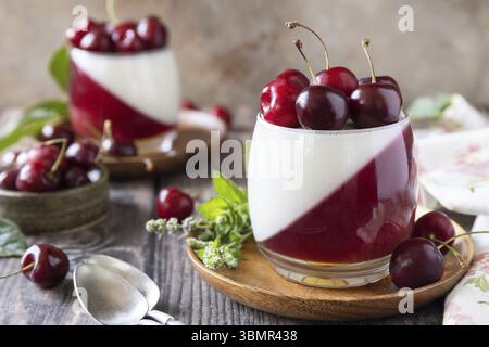 Panna cotta con gelatina dolce di ciliegia su un tavolo rustico. Dessert italiano, cucina casalinga. Copia spazio Foto Stock