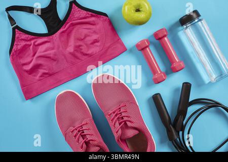 Atleta di impostare con capi di abbigliamento femminile, manubri e una bottiglia di acqua su un blu brillante background. Vista dall'alto. Copia dello spazio. Ancora in vita. Lay piatto Foto Stock