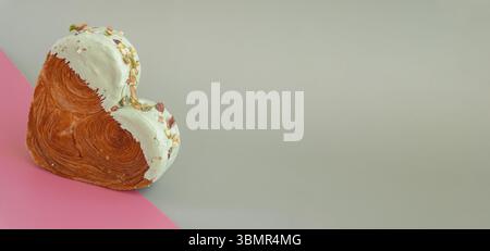 Creativi croissant isometrici per le festività di San Valentino a forma di cuore su due sfondo colorato con spazio per le copie. Pasta sfoglia nuova alla moda Foto Stock