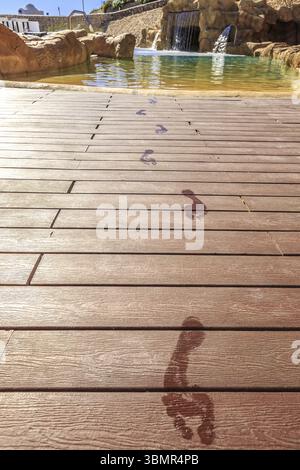 Le orme di closeup sul pavimento di legno dietro la piscina con cascata artificiale su un bellissimo resort in Egitto Foto Stock