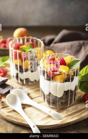 Triffle di biscotti al cioccolato con yogurt, frutti di bosco freschi e frutta. Due dessert in parfafait in vetro porzionato. Estate dieta sana colazione, snack con Foto Stock