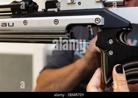 Landkreis Osnabrück, Deutschland 25. Giu 2025: Im Bild: Eine Nahaufnahme zeigt den hochpräzisen Abzugsmechanismus eines Sportgewehrs, wahrscheinlich eines Luftgewehrs, das von einer person mit sorgfältiger Handhabung gehalten wird. Der Fokus liegt auf den feinen Justiermöglichkeiten und der komplexen Mechanik des Abzugs, der Schussauslösung die für im Präzisionsschießsport entscheidend ist. Man erkennt die fein gearbeiteten Metallteile und Schrauben, die eine individuelle Einstein des Abzugswiderstands und des Vorwegs ermöglichen. Die Person, Die das Gewehr hält, trägt dunklen Nagellack, W Foto Stock