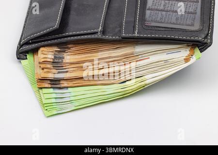 Una borsa nera trabocca di banconote e banconote in euro Foto Stock