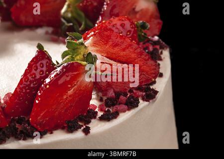 Cheesecake con fragole. Torta decorata con fragole. Deliziosa cheesecake decorata con fragole fresche. Sfondo nero. Natura morta. Foto Stock