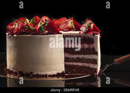 La torta di fragole su uno sfondo nero. Ancora in vita. La torta con la glassa bianca e fragole fresche Foto Stock