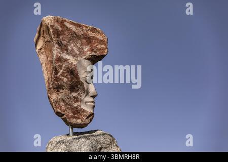 Impressionante statua di pietra di granito contro un cielo blu alla luce del sole Foto Stock