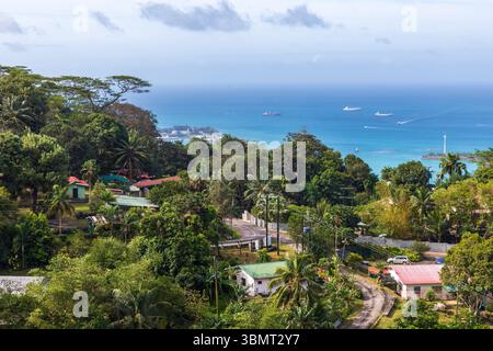 Un'isola tropicale caratterizzata da una costa vibrante, case accoccolate nel verde e un oceano tranquillo. Costa dell'isola di Mahe, Seychelles Foto Stock