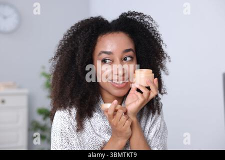 Bella donna brasiliana con barattolo di crema al collagene al chiuso Foto Stock